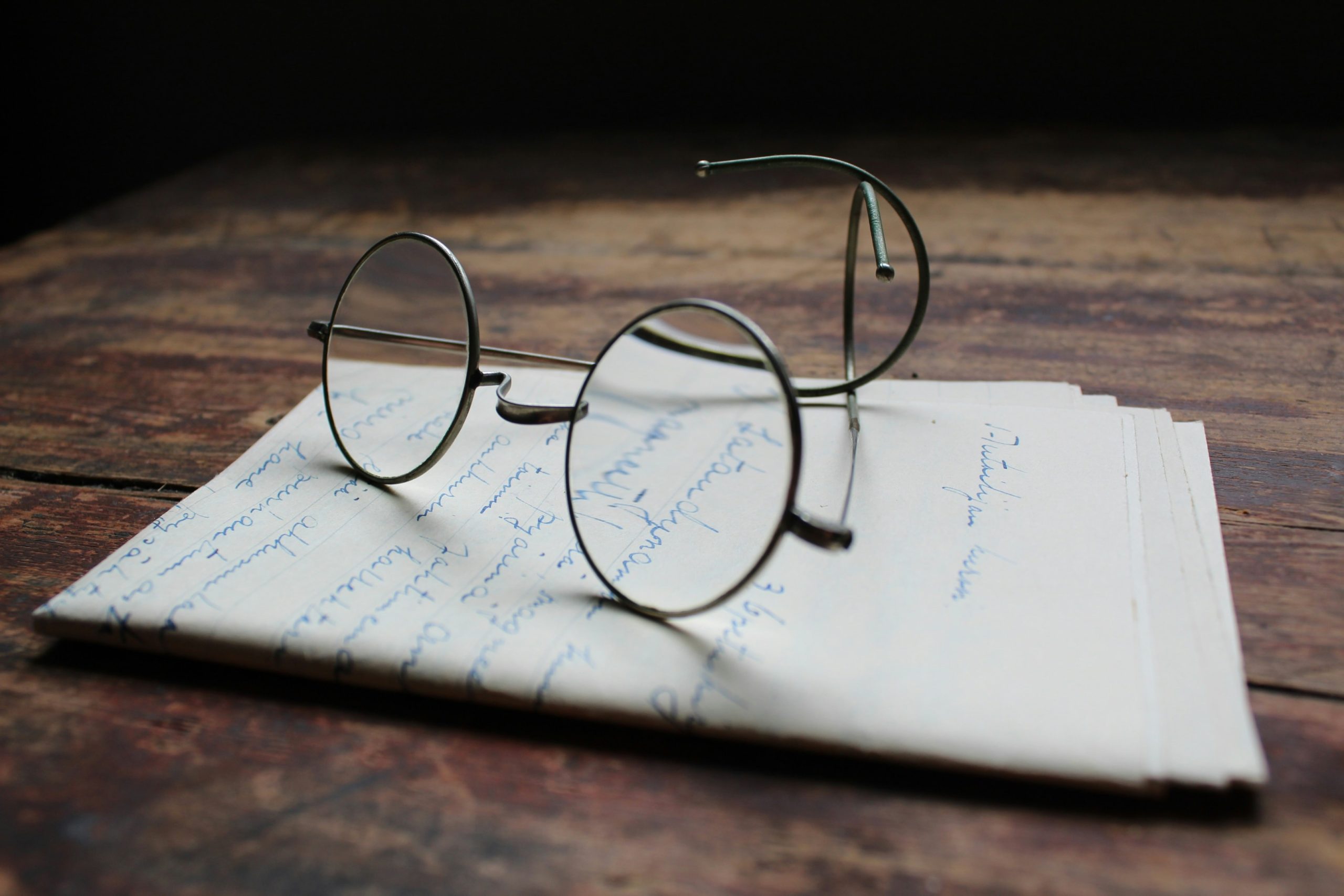 An image of black glasses placed on top of a piece of paper with notes on it.