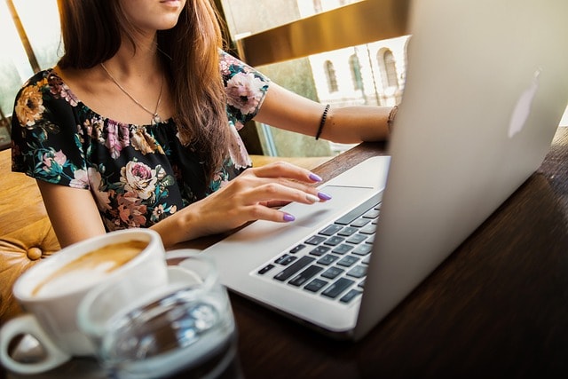 A woman working on her laptop with a cup of coffee next to her.