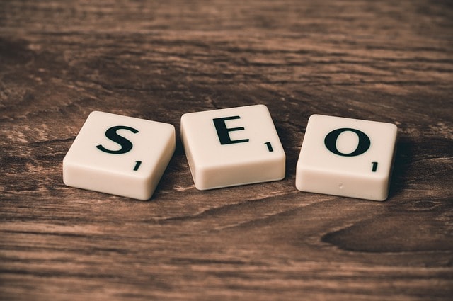 Scrabble tiles spelling the word "SEO" on a wooden surface.