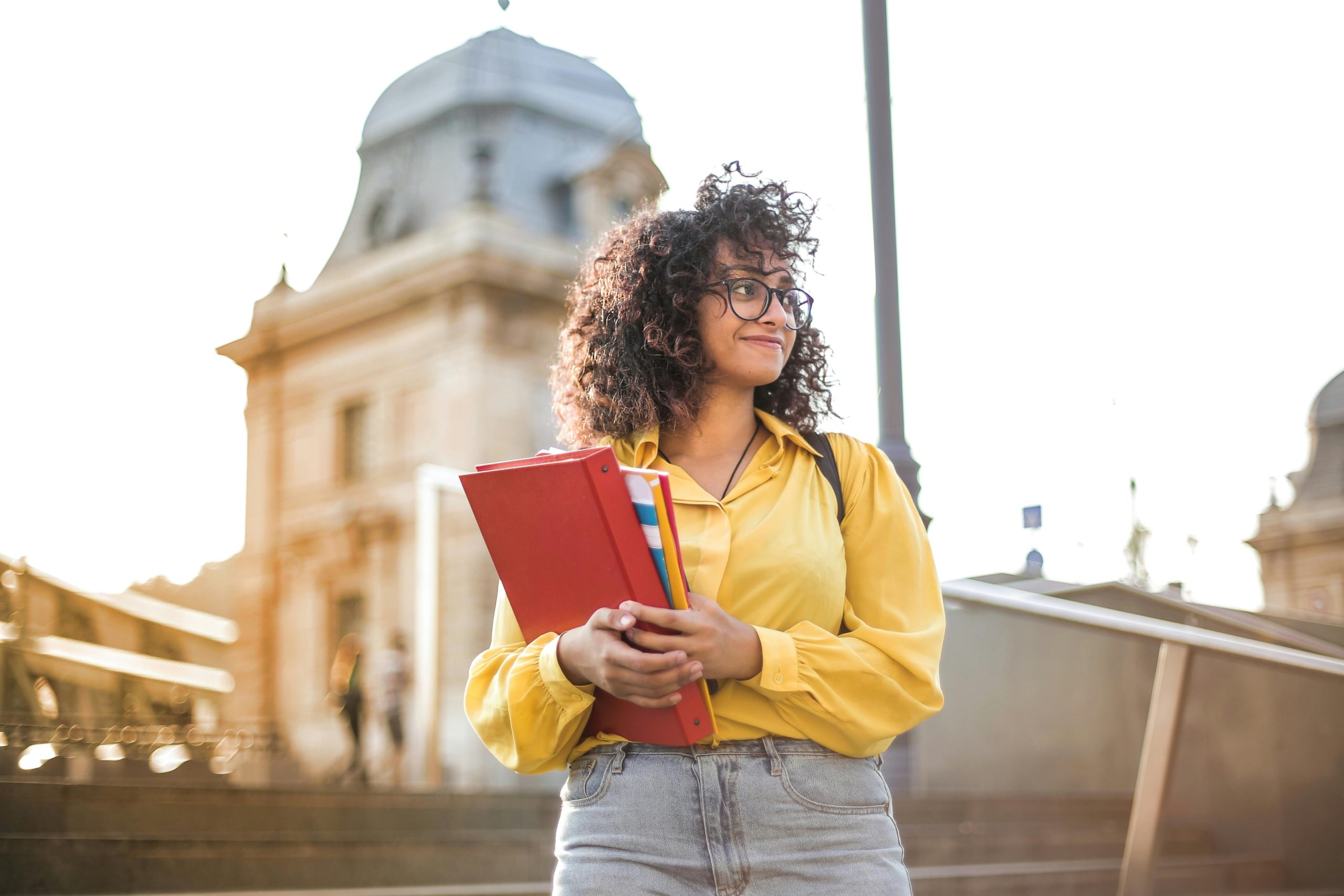 Ina universitata studento tenas siajn universitatajn librojn kaj ridetas.