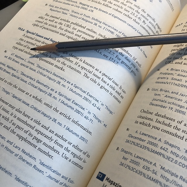 An open book with a pencil lying on top of it.