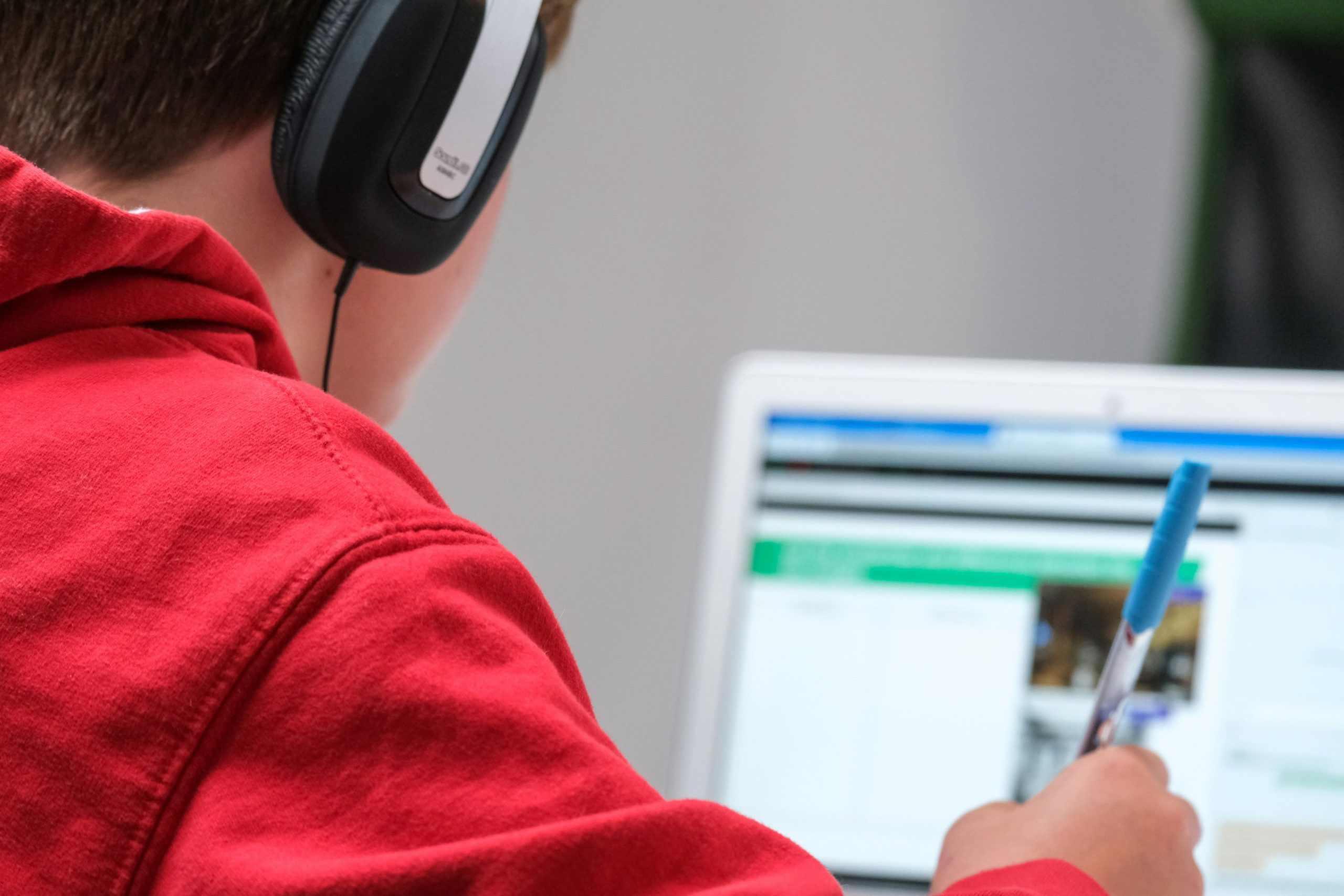 A person studying in front of a laptop with headphones on.