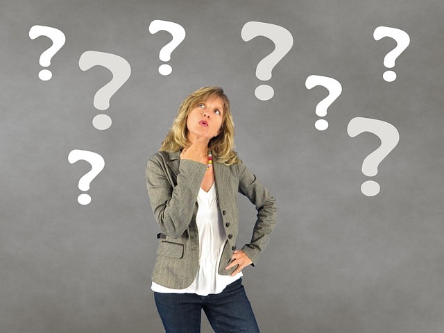 A woman surrounded by white question marks on a grey background.