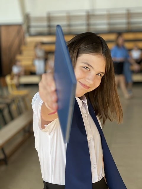 A student holding a blue notebook and smiling.