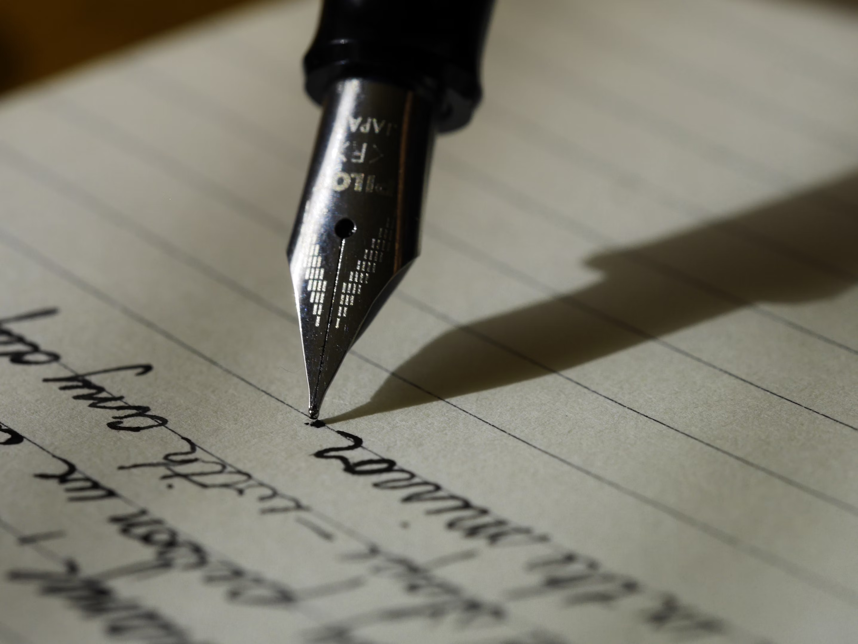 A close-up of a fountain pen writing on lined paper.