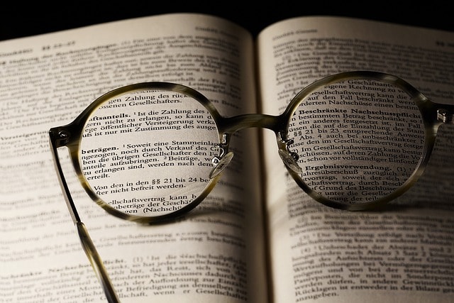 An open book with a pair of reading glasses on top of it.