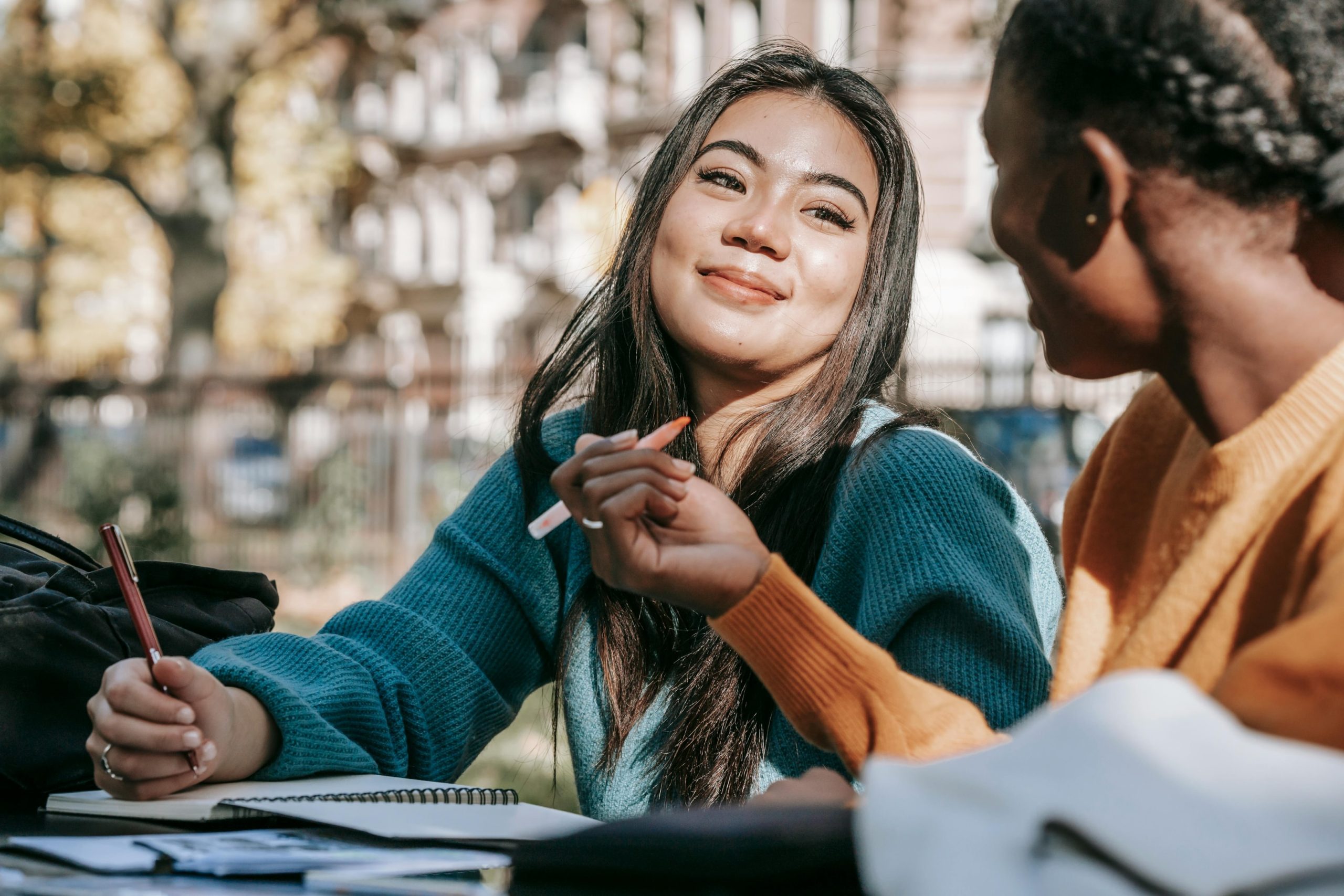 Two students smiling while working on a project outdoors. 