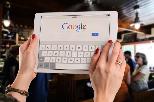 A person holding up a tablet displaying the Google Search page.