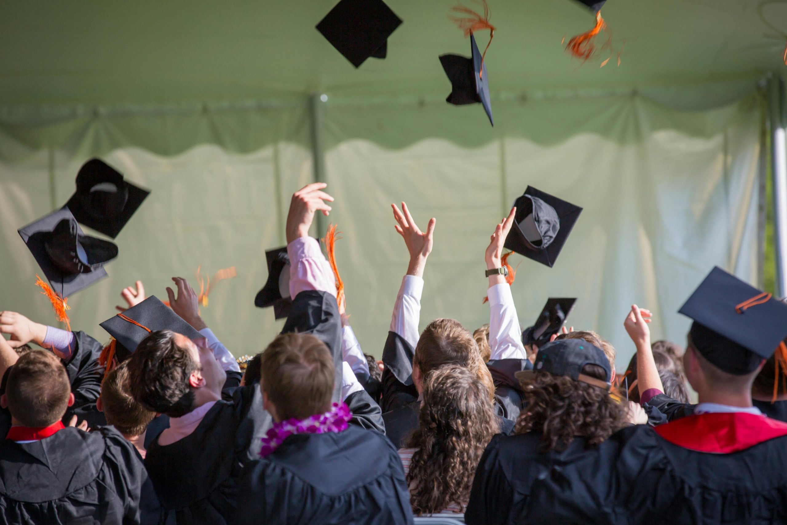 Graduates throwing their graduation caps into the air.