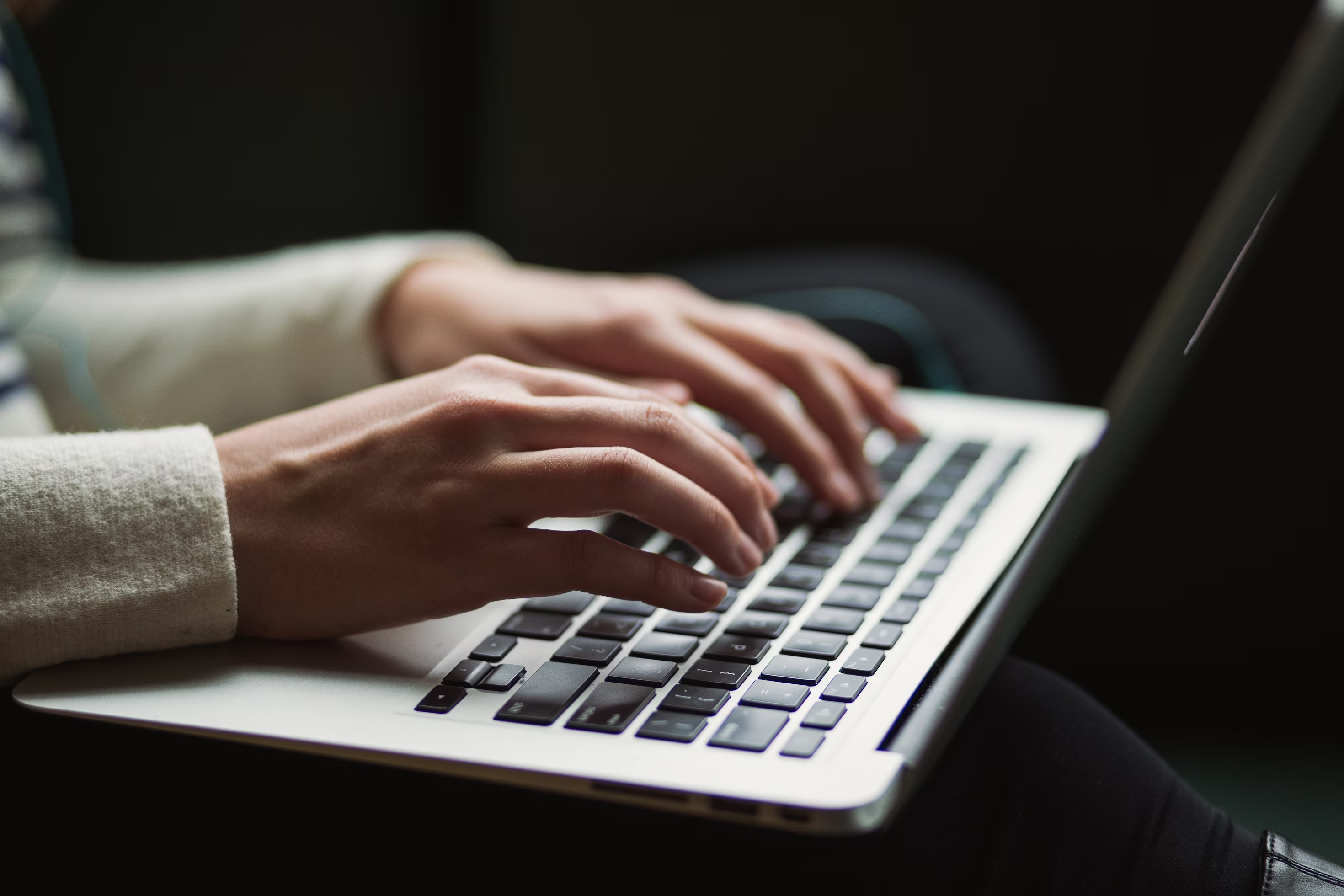 A close-up of a person typing on a laptop keyboard.