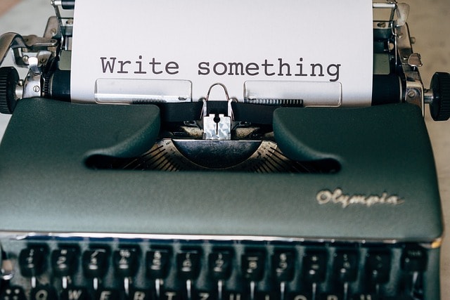 A typewriter with a piece of paper inside it saying "Write something."