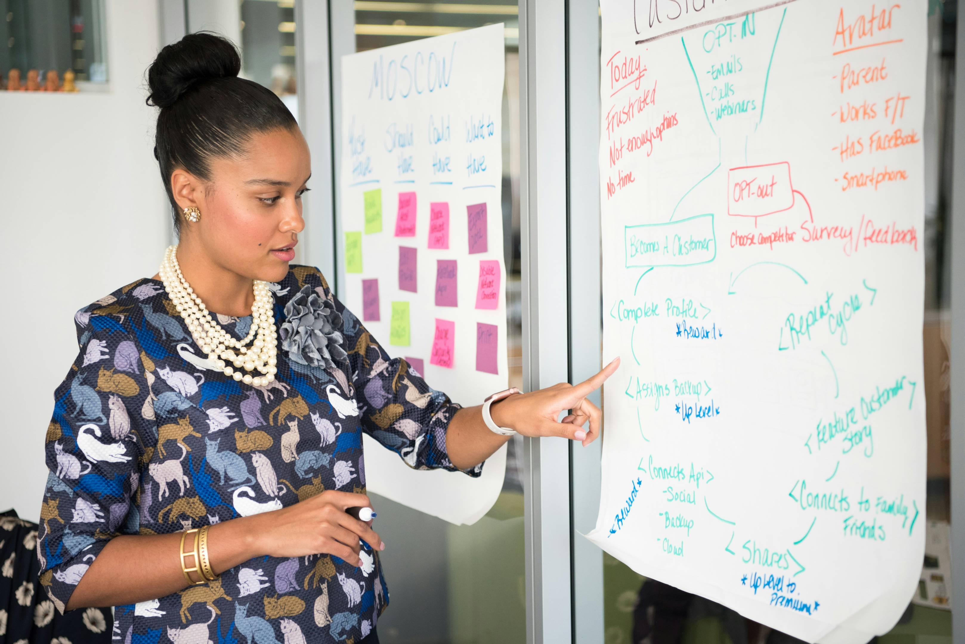 A woman presenting information from a large piece of paper displaying a flow chart.