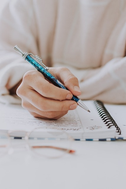 A person writing with a pen in a notebook.