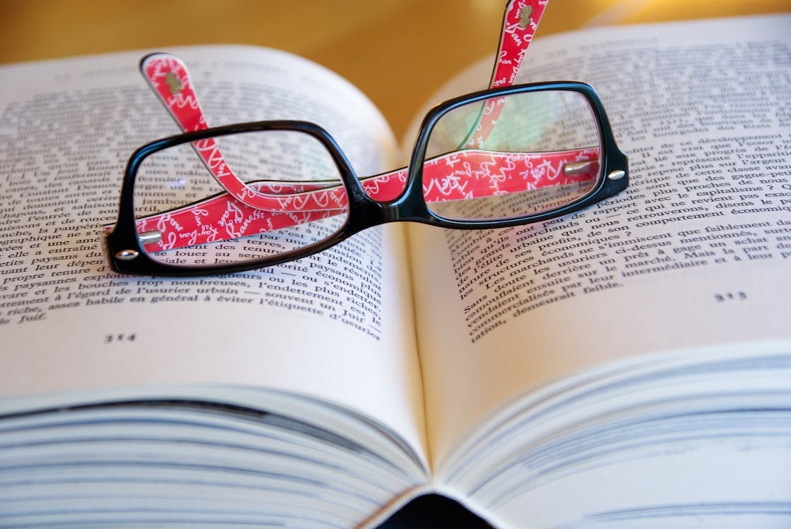 Black reading glasses laying on a novel.