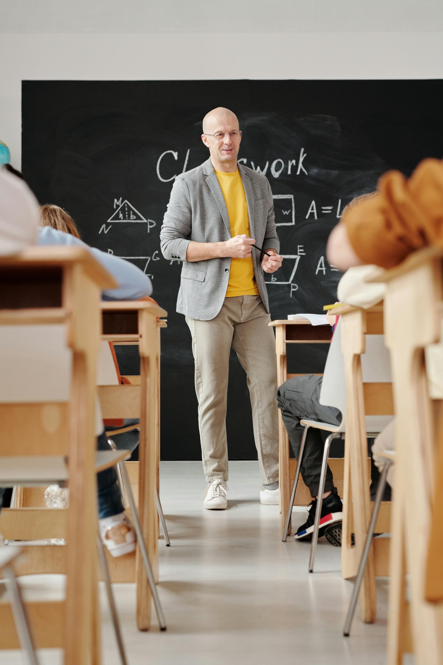 A teacher standing in front of a blackboard in a classroom full of students.