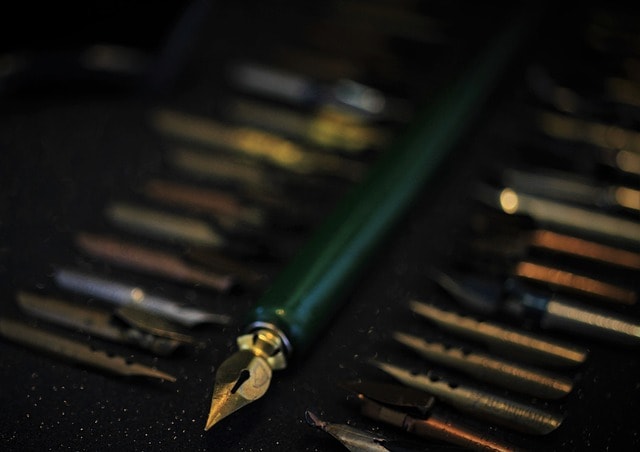 A green fountain pen surrounded by many fountain pen tips.