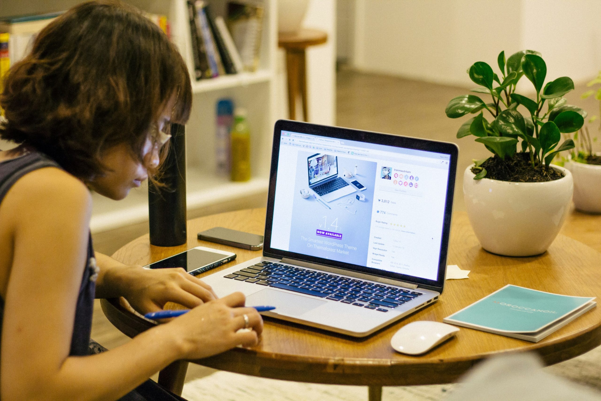 A person sitting in front of a laptop while holding a pen.