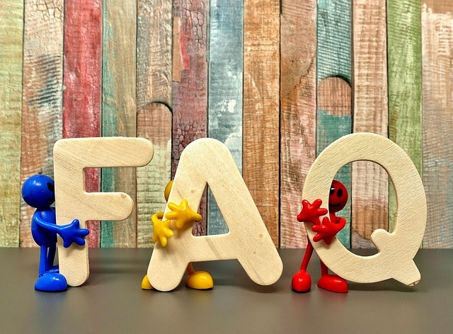 The word "FAQ" in front of mutlicolored wooden planks with each letter being hugged by a little figure.