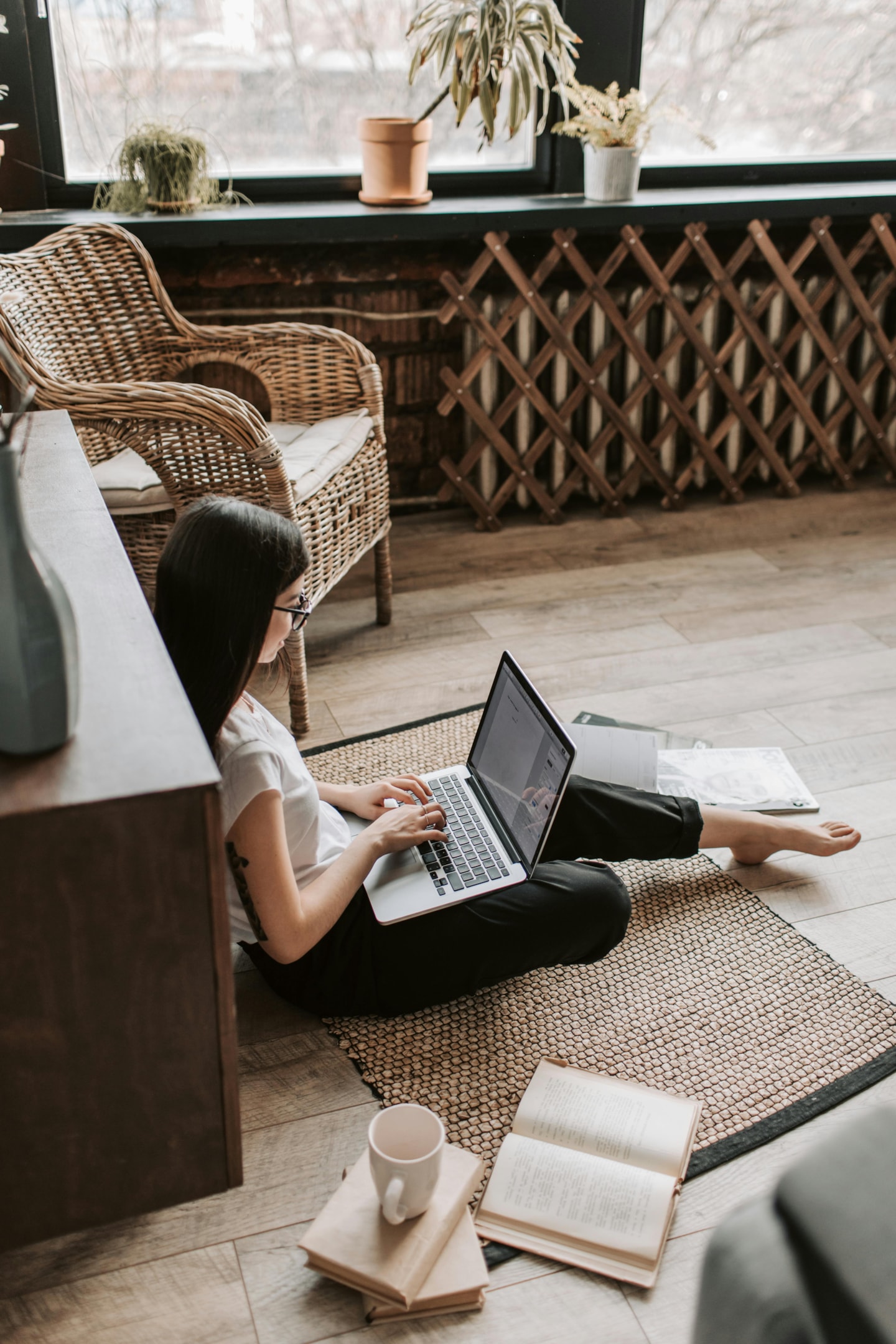  A young woman using her laptop while sitting on the floor of her living room. 