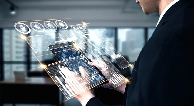 A man looking at graphs and charts on a transparent tablet.