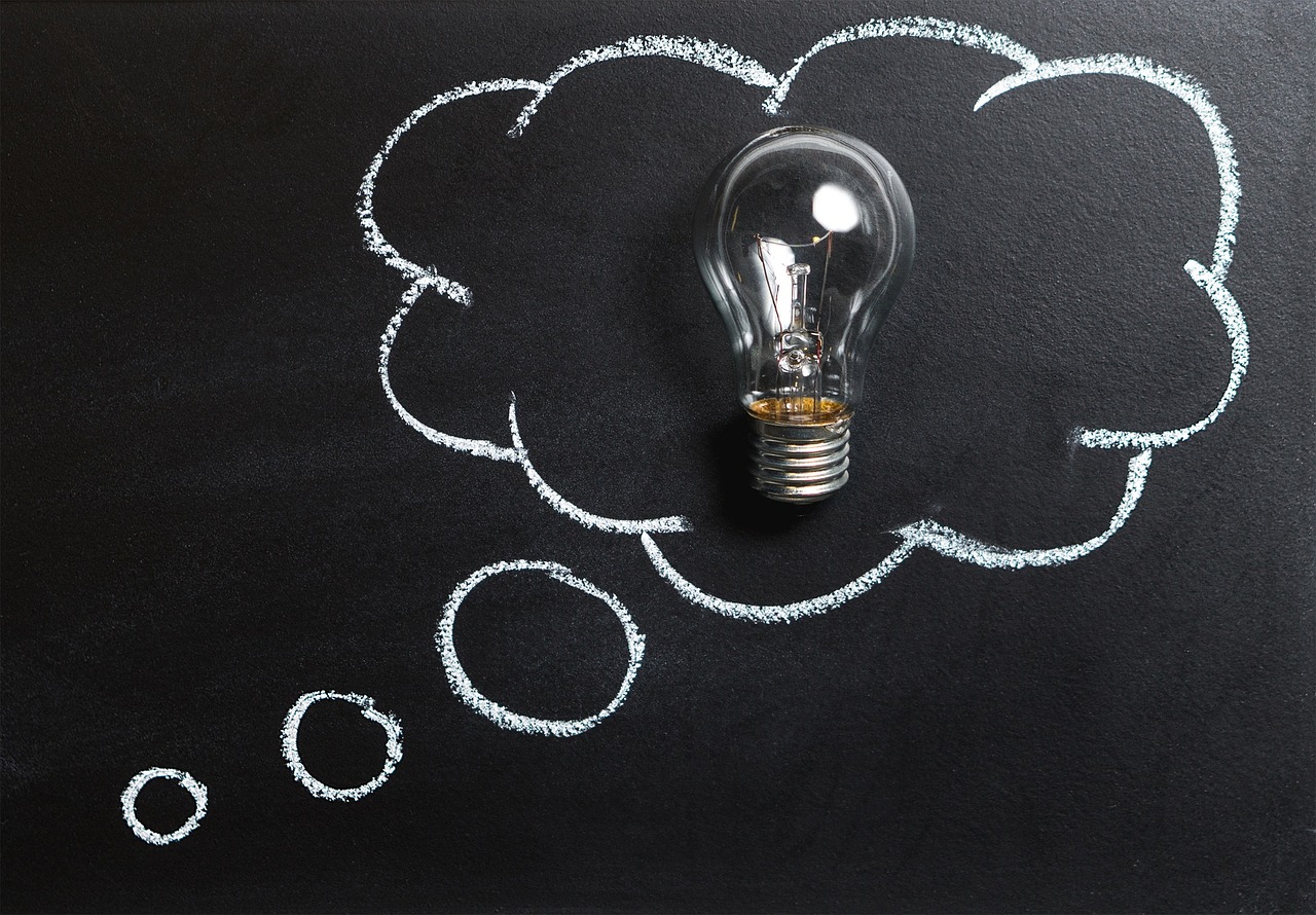 A thought bubble drawn on a black chalkboard with a light bulb in the center.