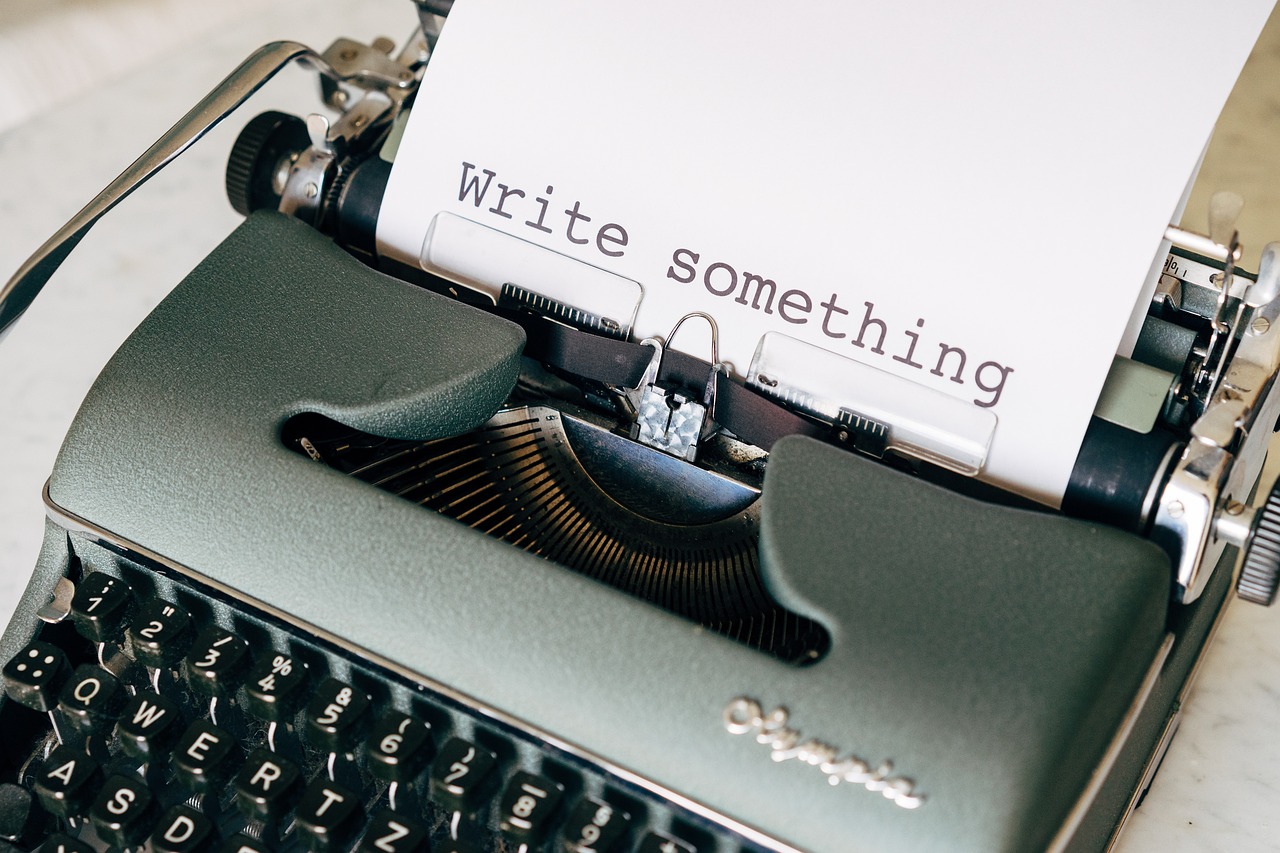 A typewriter with a piece of paper inside saying "write something."