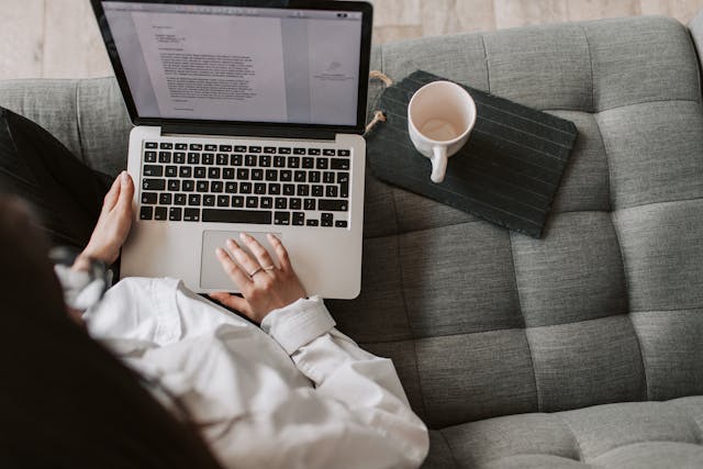 An overhead shot of a woman on a laptop editing an essay. 