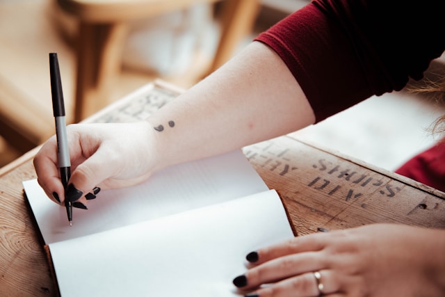 A person writing an outline for their essay in their notebook. 