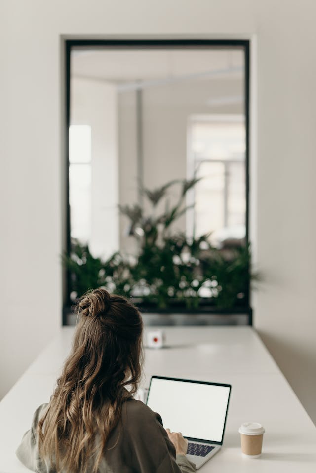 A woman sitting at her laptop writing an essay. 