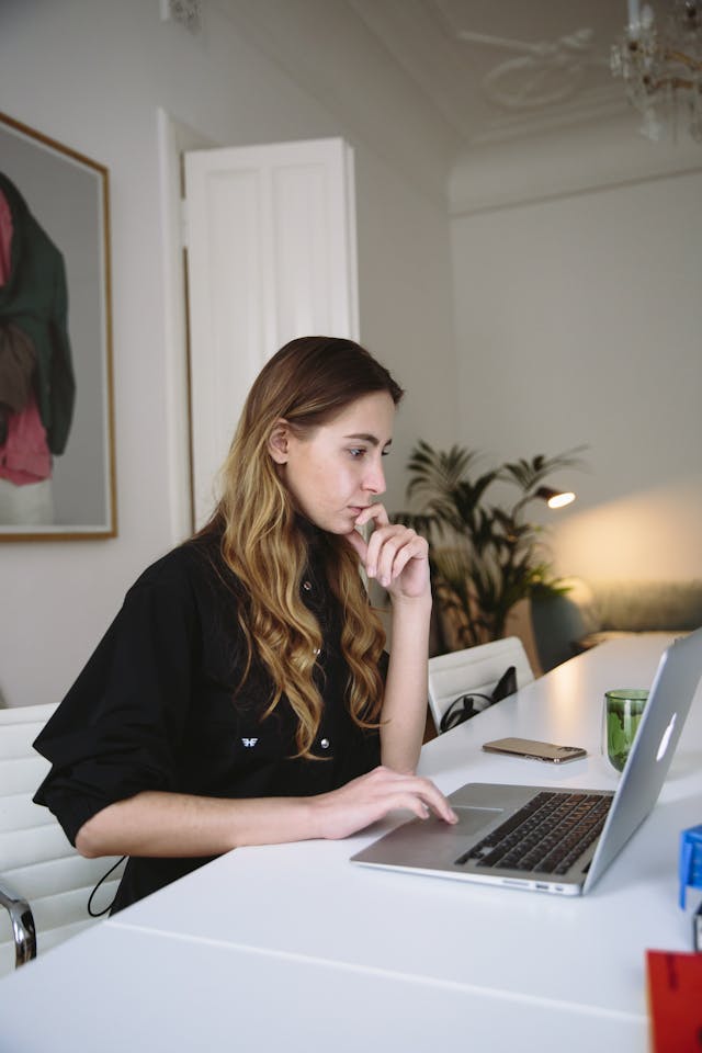 Photo of a woman using her laptop at a desk in her home. 