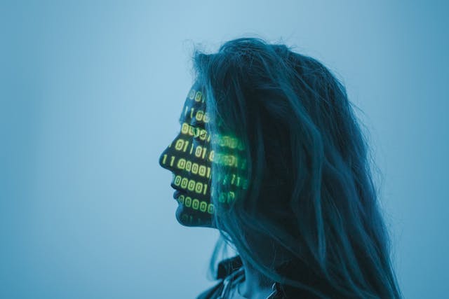 A woman’s face with computer code illuminated on it. 