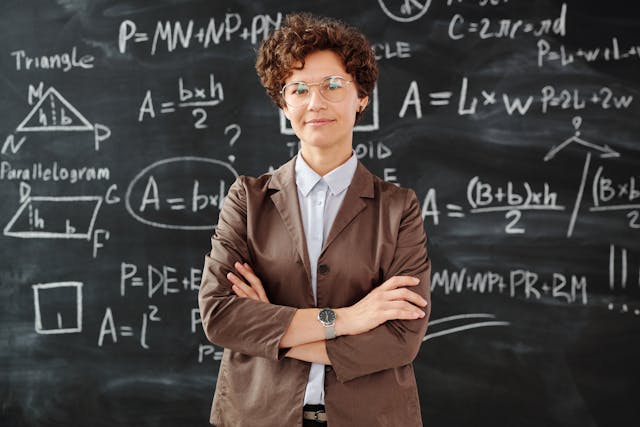 A woman standing in front of a blackboard that has math equations written on it. 