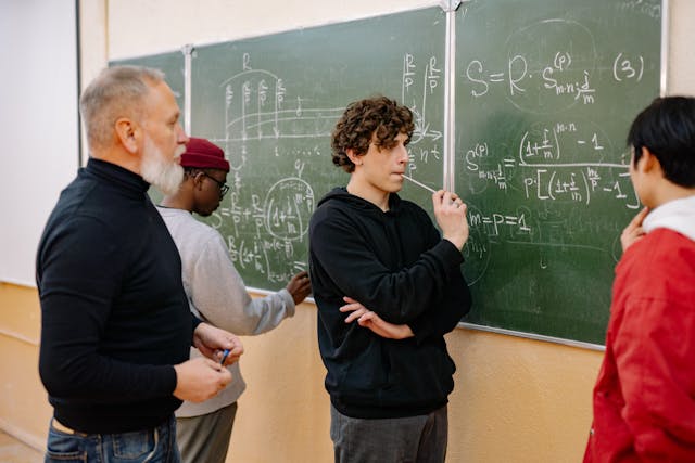 A group of people standing in front of a blackboard that has math equations on it. 