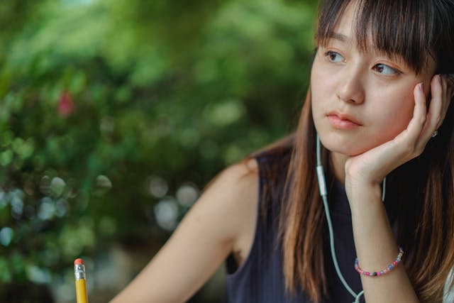 A student with her headphones in, gazing off into the distance, thinking of ways to make her essay longer. 