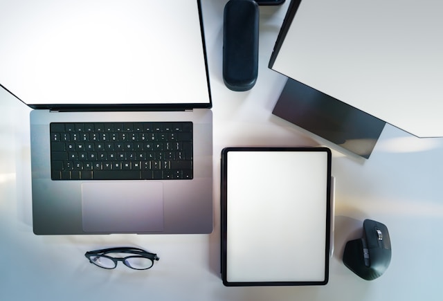 Top view of a laptop, iPad, and desktop monitor with blank screens. 