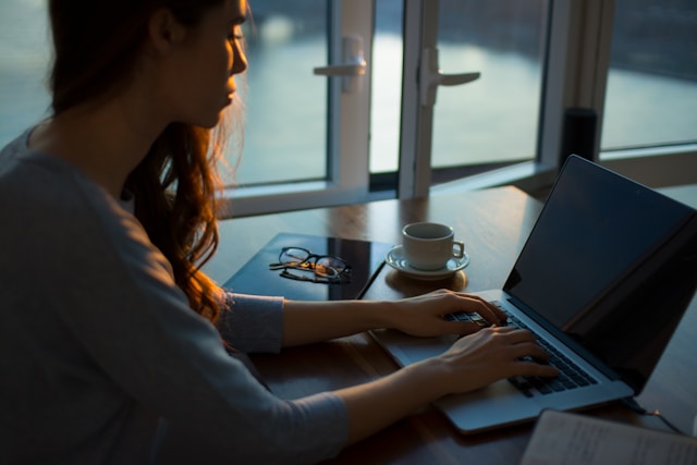 A woman typing on her laptop sitting at a desk. 