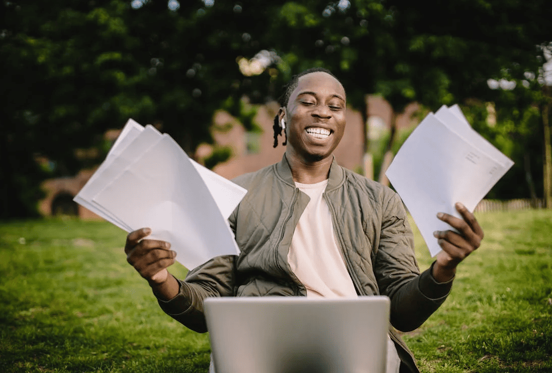 A man holding some pieces of paper and triumphantly smiling.