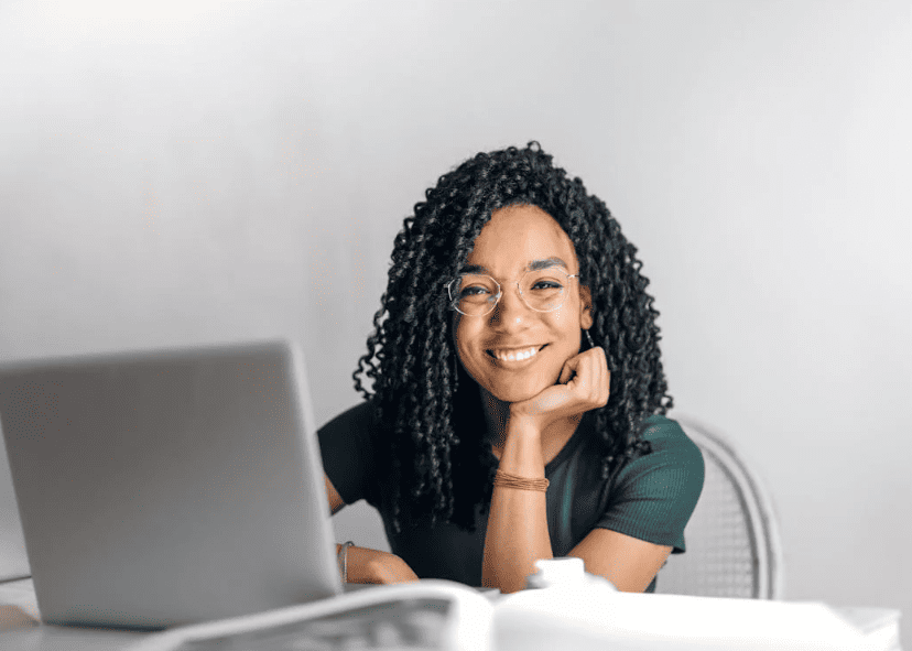 A woman sitting next to a gray laptop and smiling.