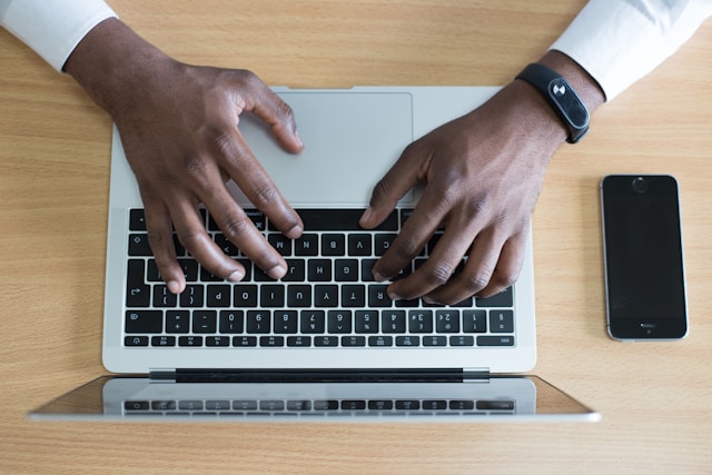 An aerial view of a person’s hands typing on a laptop. 