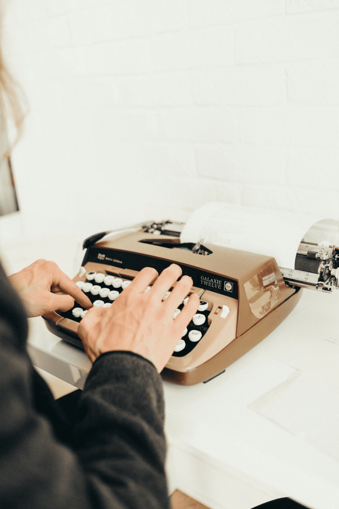 A person typing on an old fashioned typewriter