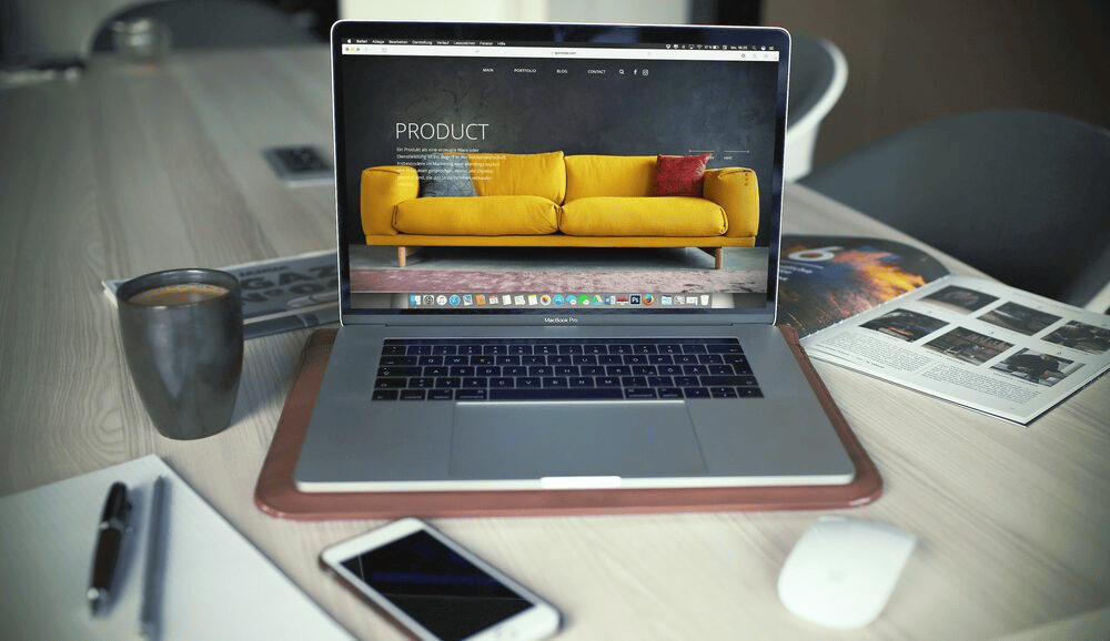 A laptop on a desk displaying a yellow sofa and the word "product" above it.