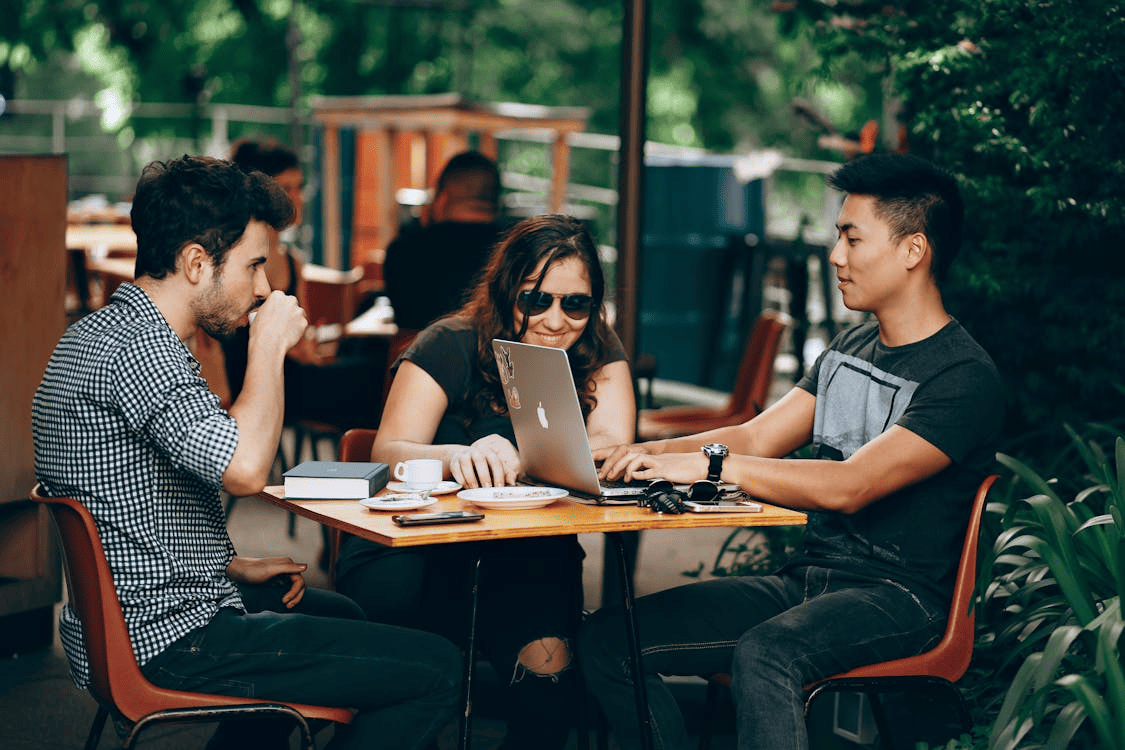 College students working outside on a desk and drinking coffee.