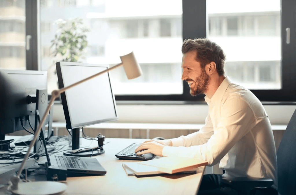 A man working on their computer and smiling.