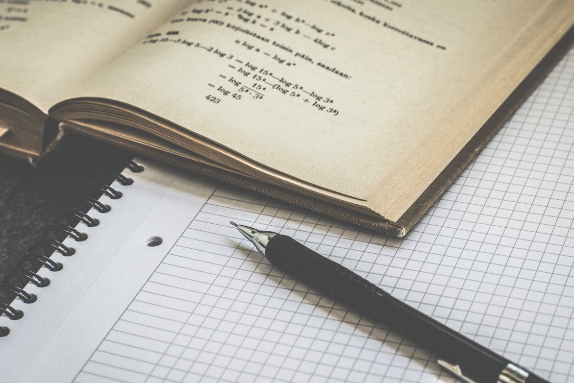 A pen and paper next to a mathematics book. 