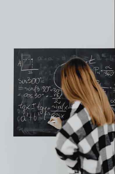 A girl doing maths on a blackboard. 