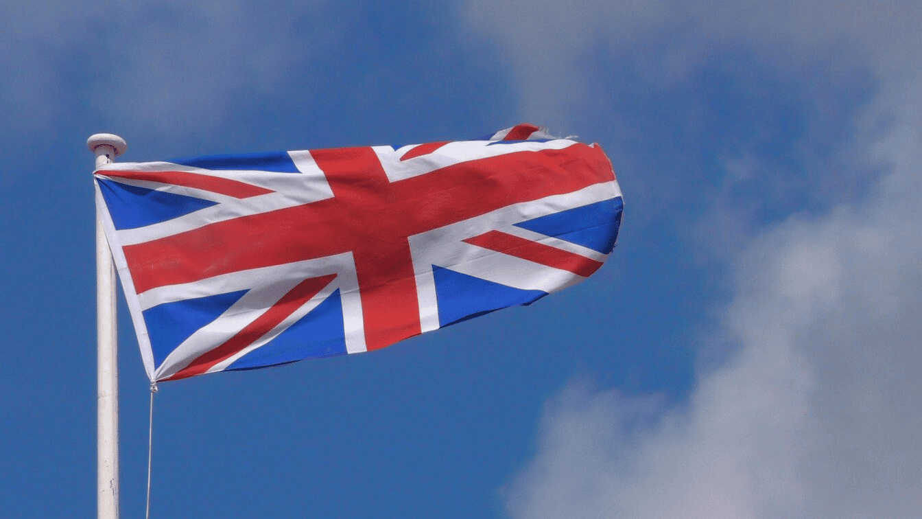 Image of the British union jack flag on a flagpole moving in the wind.