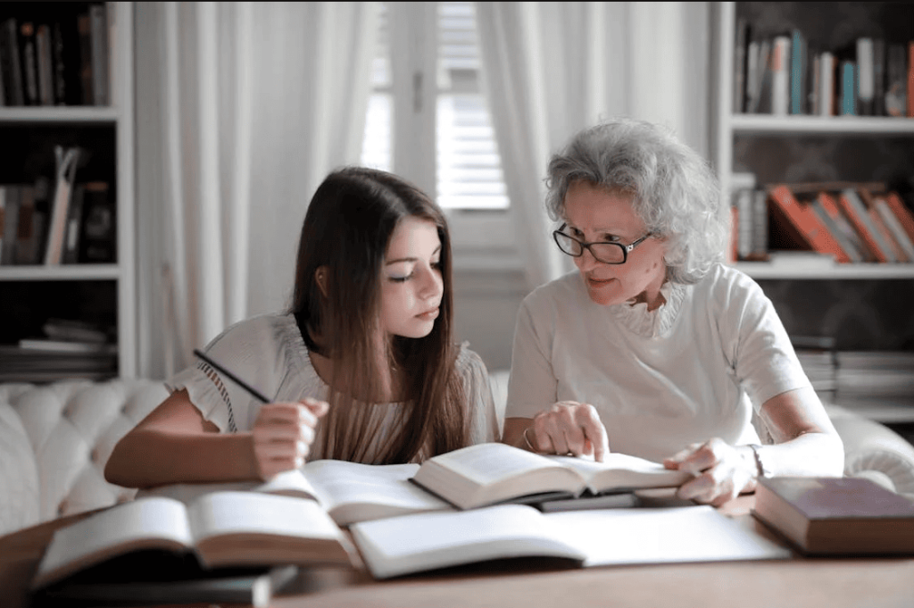 A student doing their homework with an elderly person helping. 