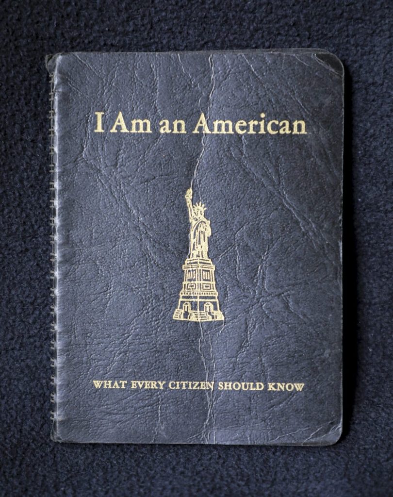 A passport with the statue of liberty on it saying "I am an American."