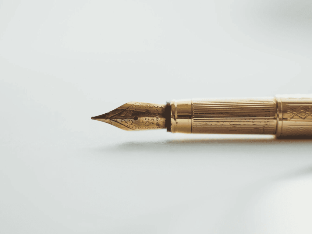 A brass quilt pen on a white surface.