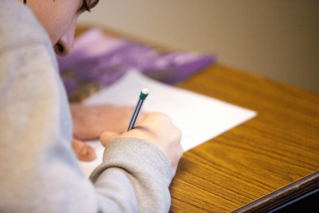 A person writing something on a white piece of paper.